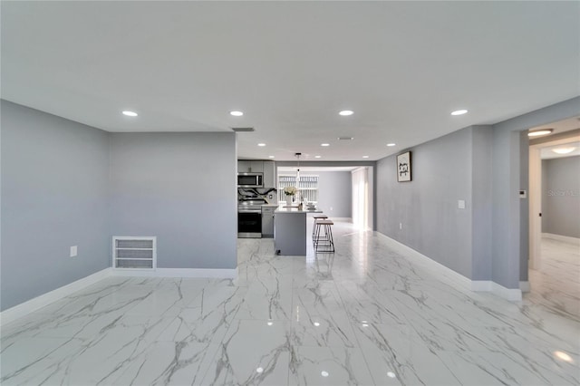 kitchen with appliances with stainless steel finishes, a center island, pendant lighting, and a kitchen bar