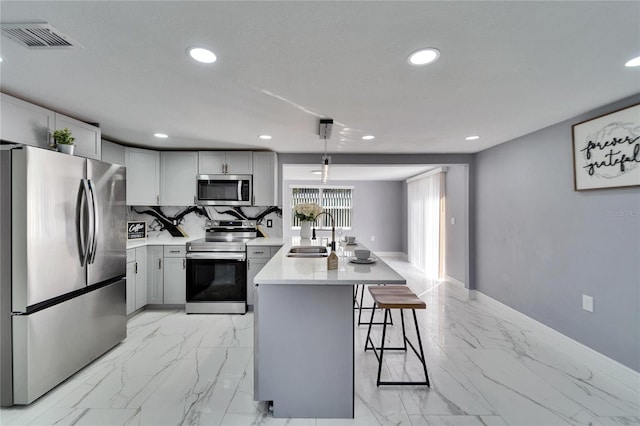 kitchen with gray cabinets, a kitchen island, appliances with stainless steel finishes, pendant lighting, and sink