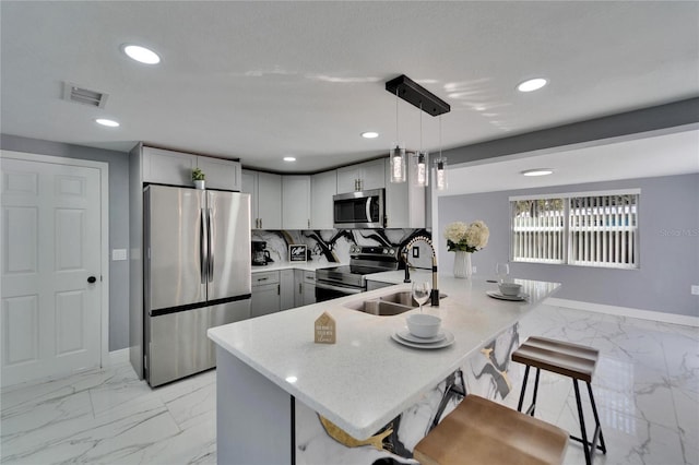 kitchen featuring appliances with stainless steel finishes, pendant lighting, sink, gray cabinetry, and decorative backsplash