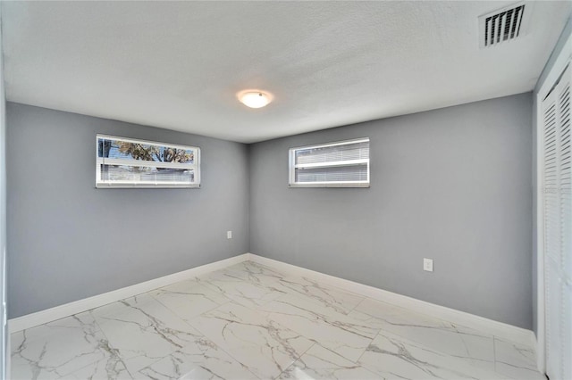 unfurnished room featuring a textured ceiling