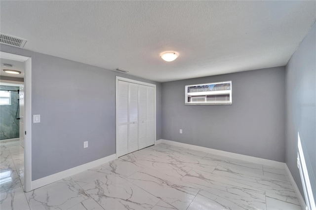 unfurnished bedroom featuring a closet, multiple windows, and a textured ceiling