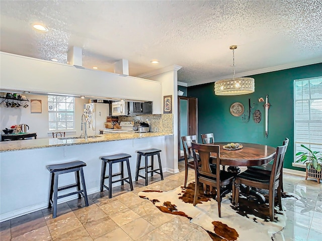 dining room featuring crown molding, sink, and a textured ceiling