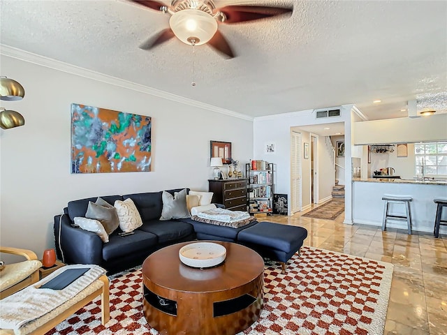 living room with ceiling fan, ornamental molding, sink, and a textured ceiling