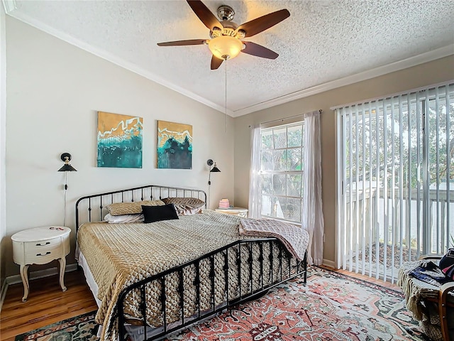 bedroom with vaulted ceiling, a textured ceiling, access to outside, ornamental molding, and hardwood / wood-style floors