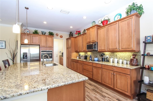 kitchen with sink, tasteful backsplash, decorative light fixtures, appliances with stainless steel finishes, and an island with sink