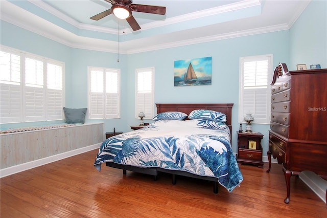 bedroom featuring ceiling fan, ornamental molding, a raised ceiling, and hardwood / wood-style floors