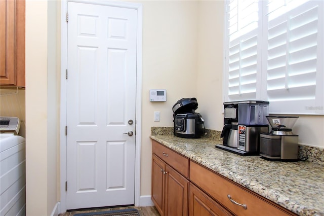 kitchen with washer / clothes dryer and light stone counters