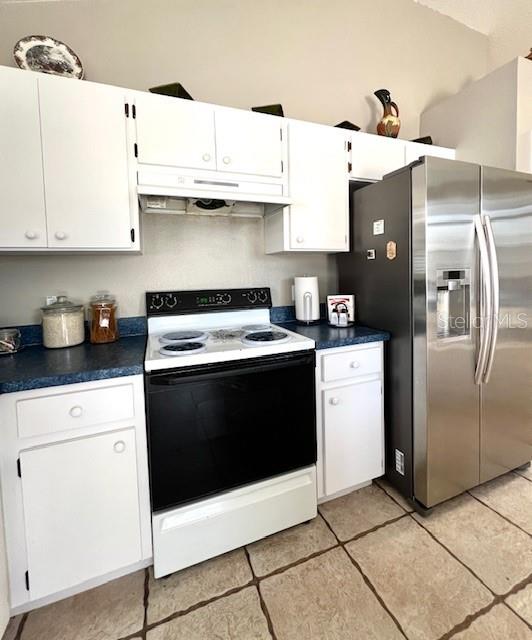 kitchen with white cabinetry, range with electric cooktop, light tile patterned flooring, and stainless steel fridge with ice dispenser