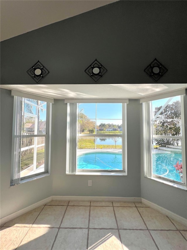 interior space with a water view, tile patterned floors, and a wealth of natural light