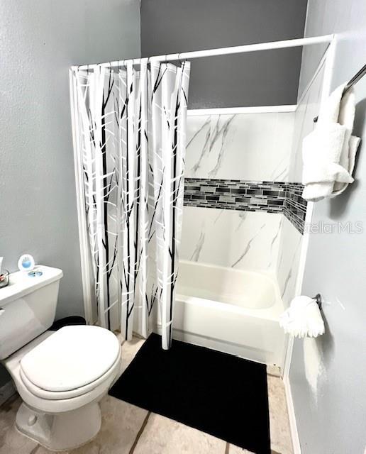 bathroom featuring tile patterned floors, toilet, and shower / bath combo