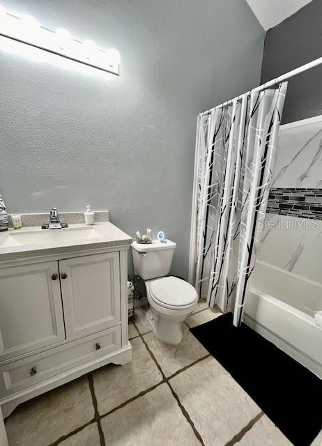 full bathroom with shower / tub combo with curtain, vanity, and toilet