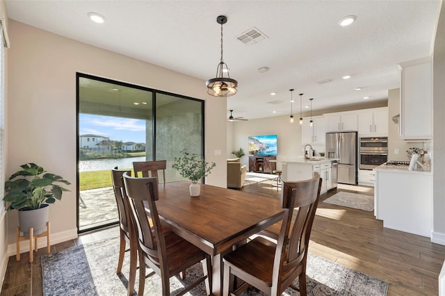 dining area featuring sink, dark wood-type flooring, and ceiling fan