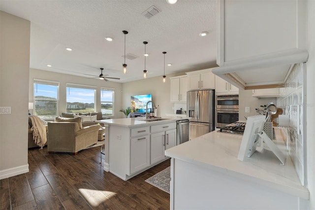 kitchen with stainless steel appliances, white cabinetry, sink, and a center island with sink