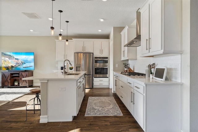 kitchen with sink, a breakfast bar area, decorative light fixtures, a center island with sink, and appliances with stainless steel finishes