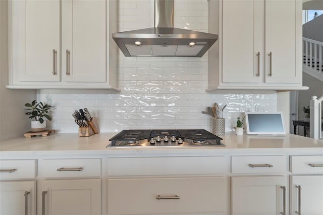 kitchen featuring stainless steel gas stovetop, extractor fan, white cabinets, and decorative backsplash