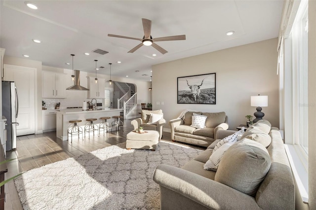 living room featuring ceiling fan, sink, and light hardwood / wood-style flooring