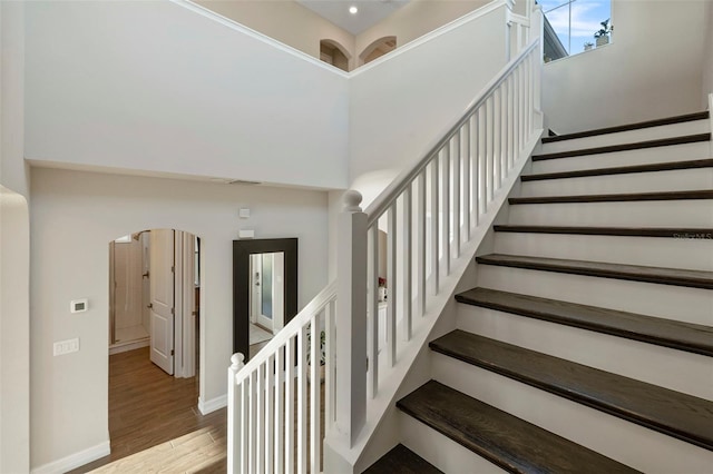 stairs with hardwood / wood-style floors and a towering ceiling