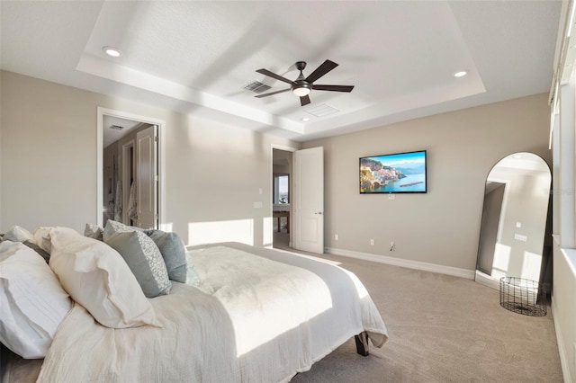 carpeted bedroom with a raised ceiling and ceiling fan