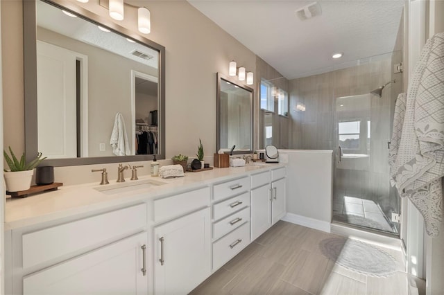 bathroom featuring a shower with door and vanity