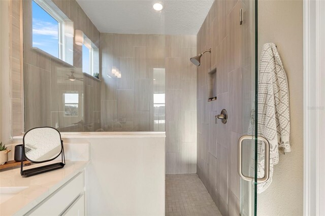 bathroom with vanity, a shower with shower door, and a textured ceiling