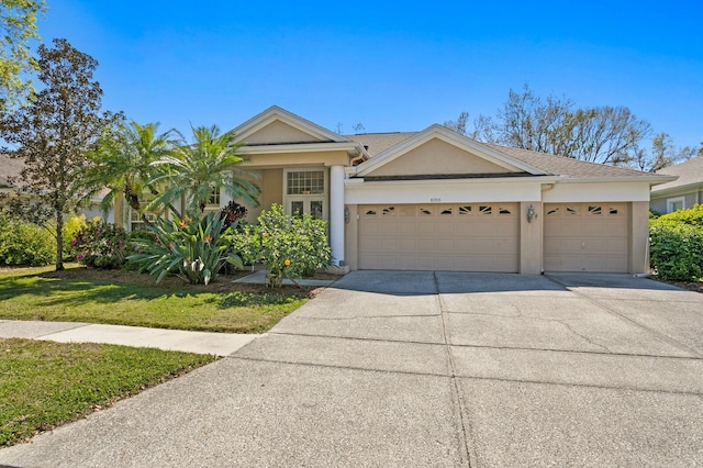 view of front facade featuring stucco siding, an attached garage, and driveway