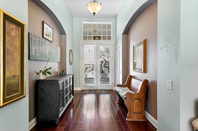 entrance foyer with baseboards, arched walkways, and dark wood-style floors