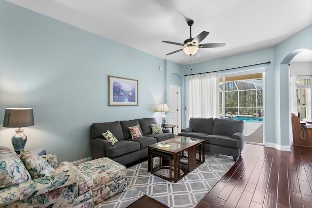 living room featuring ceiling fan, a sunroom, baseboards, and wood finished floors