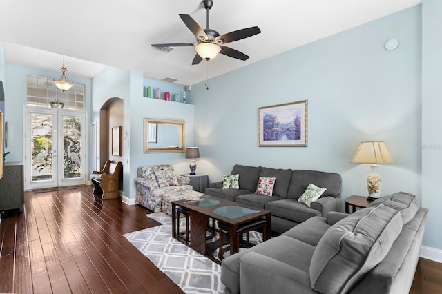 living area with a ceiling fan, visible vents, dark wood-style floors, baseboards, and arched walkways