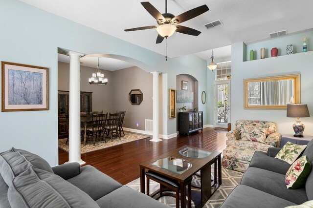 living room featuring visible vents, arched walkways, wood finished floors, and decorative columns