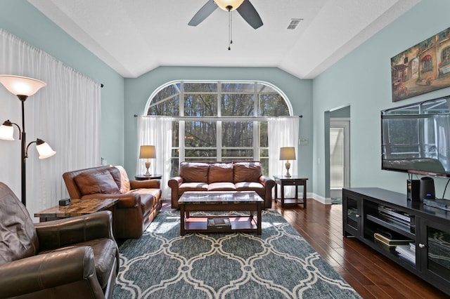 living area featuring a ceiling fan, dark wood-style floors, visible vents, baseboards, and vaulted ceiling