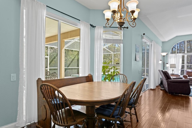 dining area with lofted ceiling, an inviting chandelier, and dark wood finished floors