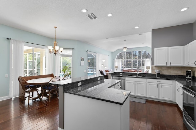 kitchen with visible vents, a kitchen island, dark wood finished floors, appliances with stainless steel finishes, and a sink