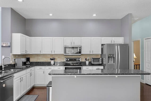 kitchen featuring dark wood finished floors, appliances with stainless steel finishes, white cabinetry, and a sink