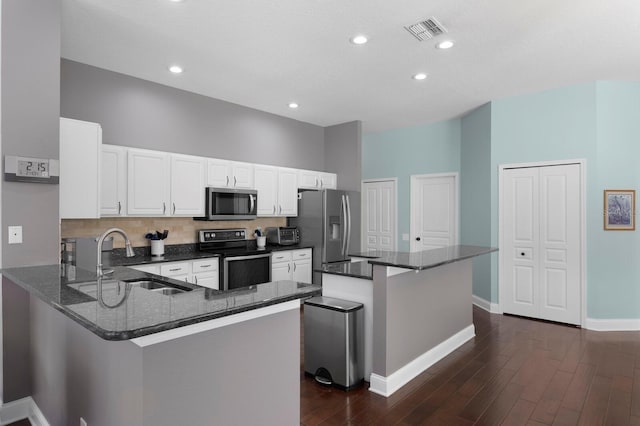 kitchen featuring visible vents, a sink, dark stone countertops, dark wood-style floors, and appliances with stainless steel finishes