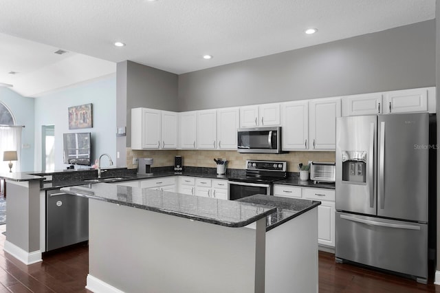 kitchen featuring a sink, dark stone counters, dark wood finished floors, and stainless steel appliances