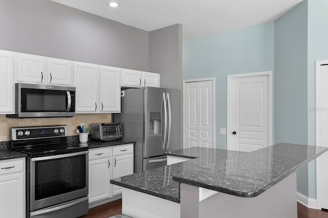 kitchen with white cabinets, tasteful backsplash, appliances with stainless steel finishes, and a kitchen island