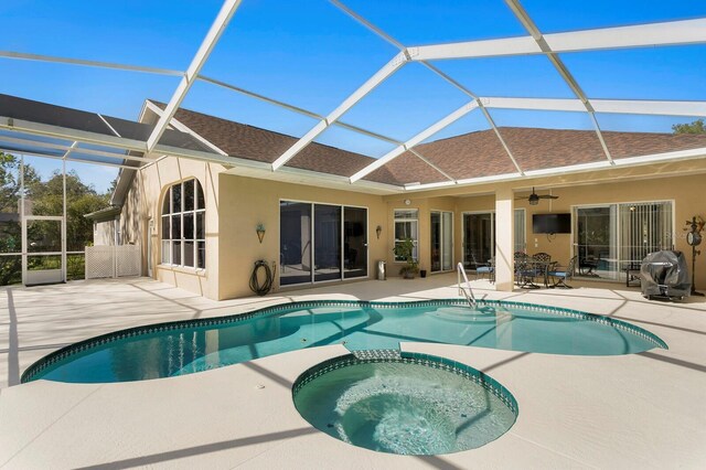 view of pool with a lanai, a pool with connected hot tub, a patio, and a ceiling fan