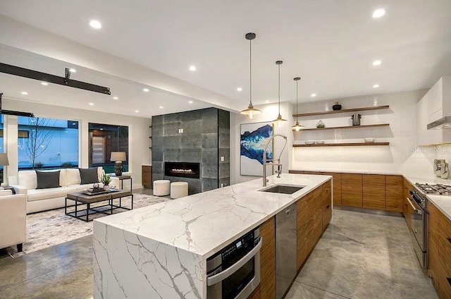 kitchen featuring a large island, concrete flooring, light stone counters, stainless steel appliances, and a fireplace