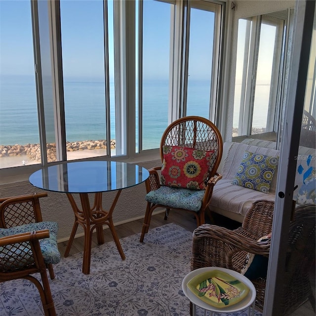 sunroom / solarium featuring a water view and a beach view