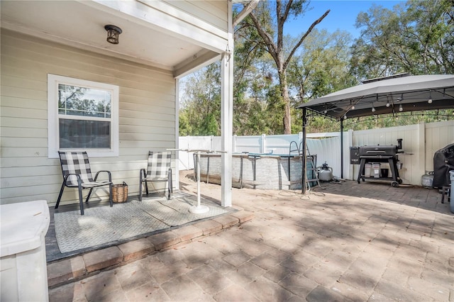 view of patio featuring area for grilling, a fenced in pool, and a gazebo