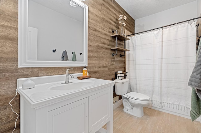 bathroom featuring wooden walls, vanity, toilet, a textured ceiling, and a shower with shower curtain