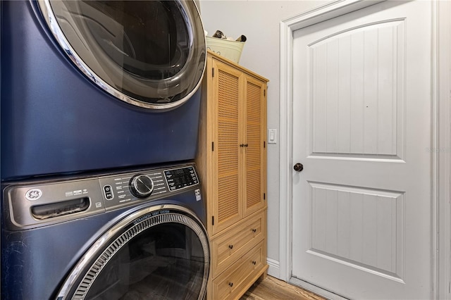 laundry room with stacked washer / drying machine and hardwood / wood-style floors