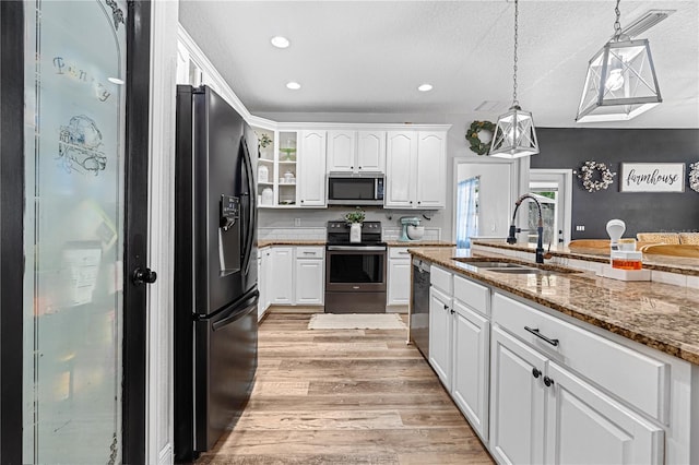 kitchen featuring sink, stone countertops, hanging light fixtures, appliances with stainless steel finishes, and white cabinets