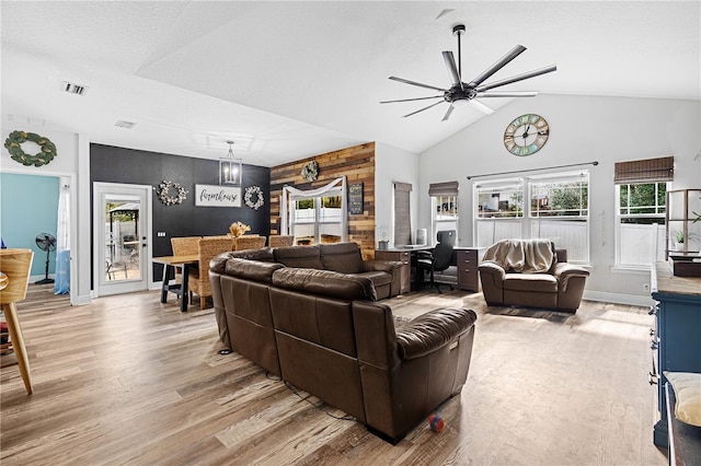 living room with ceiling fan, high vaulted ceiling, wooden walls, and hardwood / wood-style floors