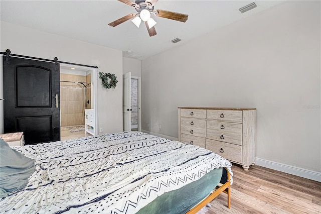 bedroom with a barn door, ceiling fan, and light wood-type flooring