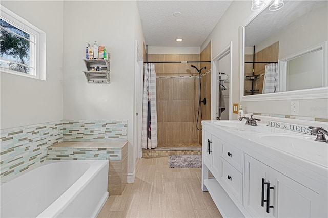 bathroom with a textured ceiling, tile walls, vanity, plus walk in shower, and hardwood / wood-style floors