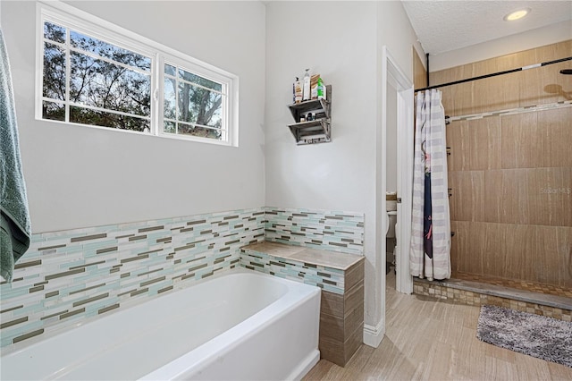 bathroom featuring separate shower and tub, tile walls, a textured ceiling, and toilet