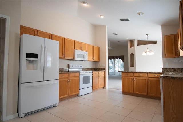 kitchen with ceiling fan with notable chandelier, pendant lighting, high vaulted ceiling, dark stone countertops, and white appliances