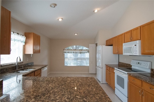 kitchen with dark stone countertops, sink, white appliances, and light tile patterned floors