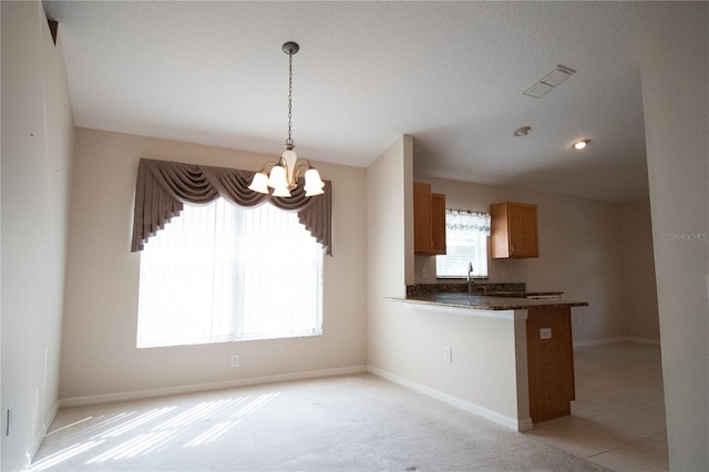 kitchen with sink, a notable chandelier, decorative light fixtures, light colored carpet, and kitchen peninsula